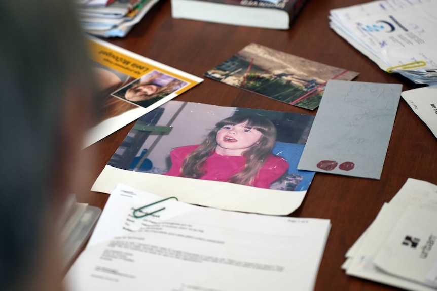 A man looking at photos of a young girl, documents and letters.