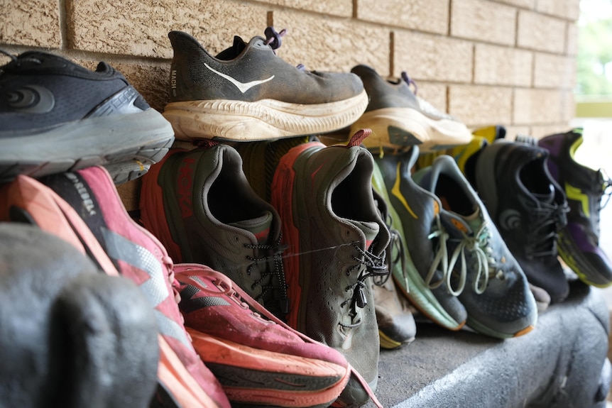 Old, worn-out runners are lined up along a brick wall.