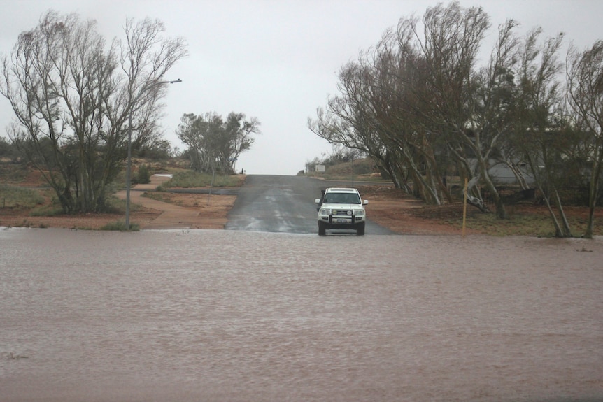 A car approaches a heavily flooded road in outback Australia.