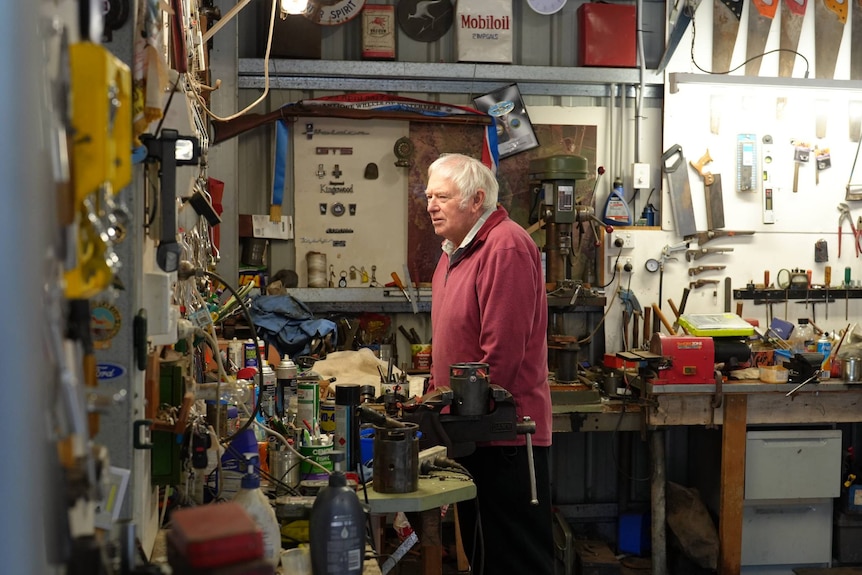 An elderly man stands in his garage.