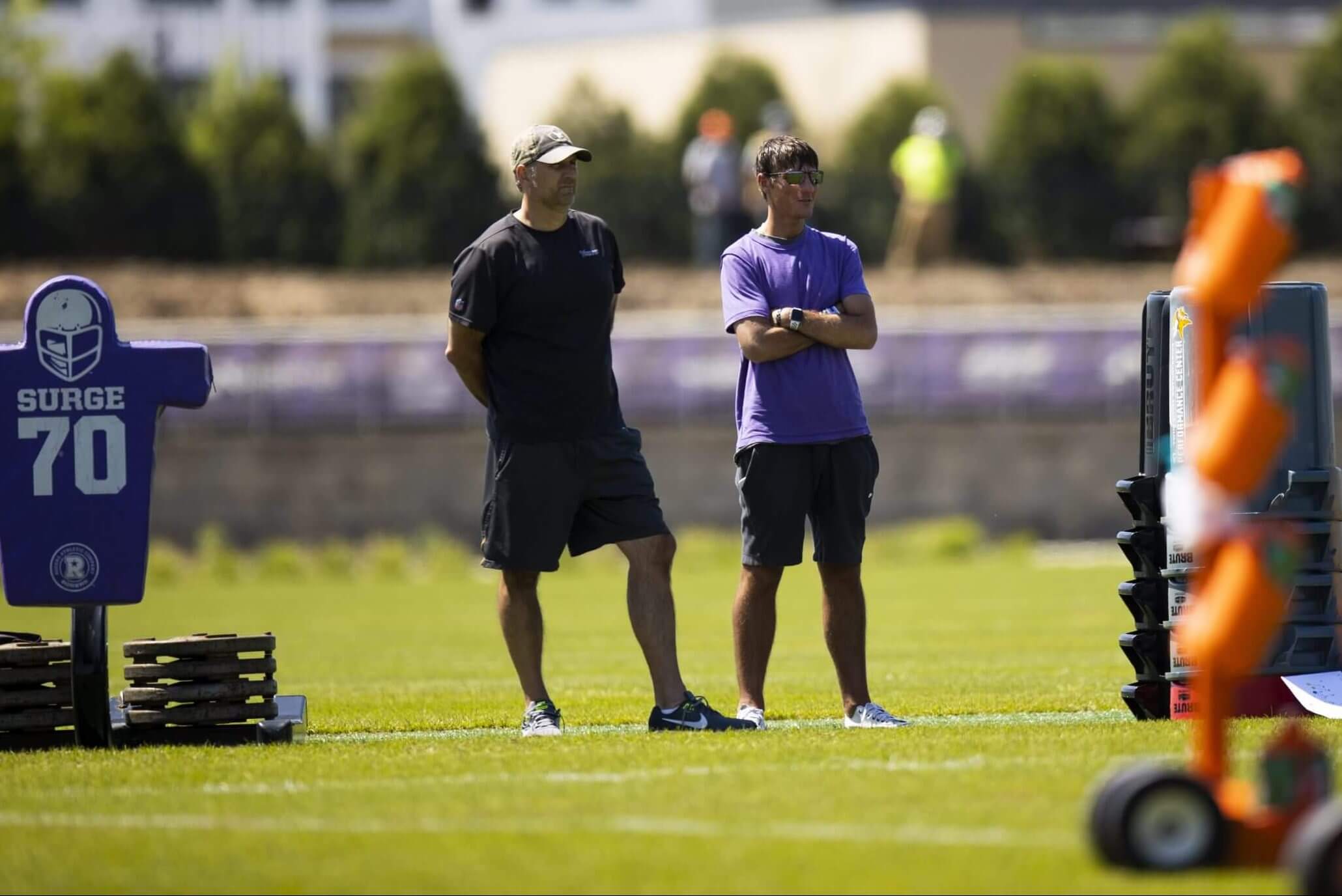 Rob Brzezinski stands on a practice field with senior manager of team operations Chuck Petersen during an OTA practice in June 2021.