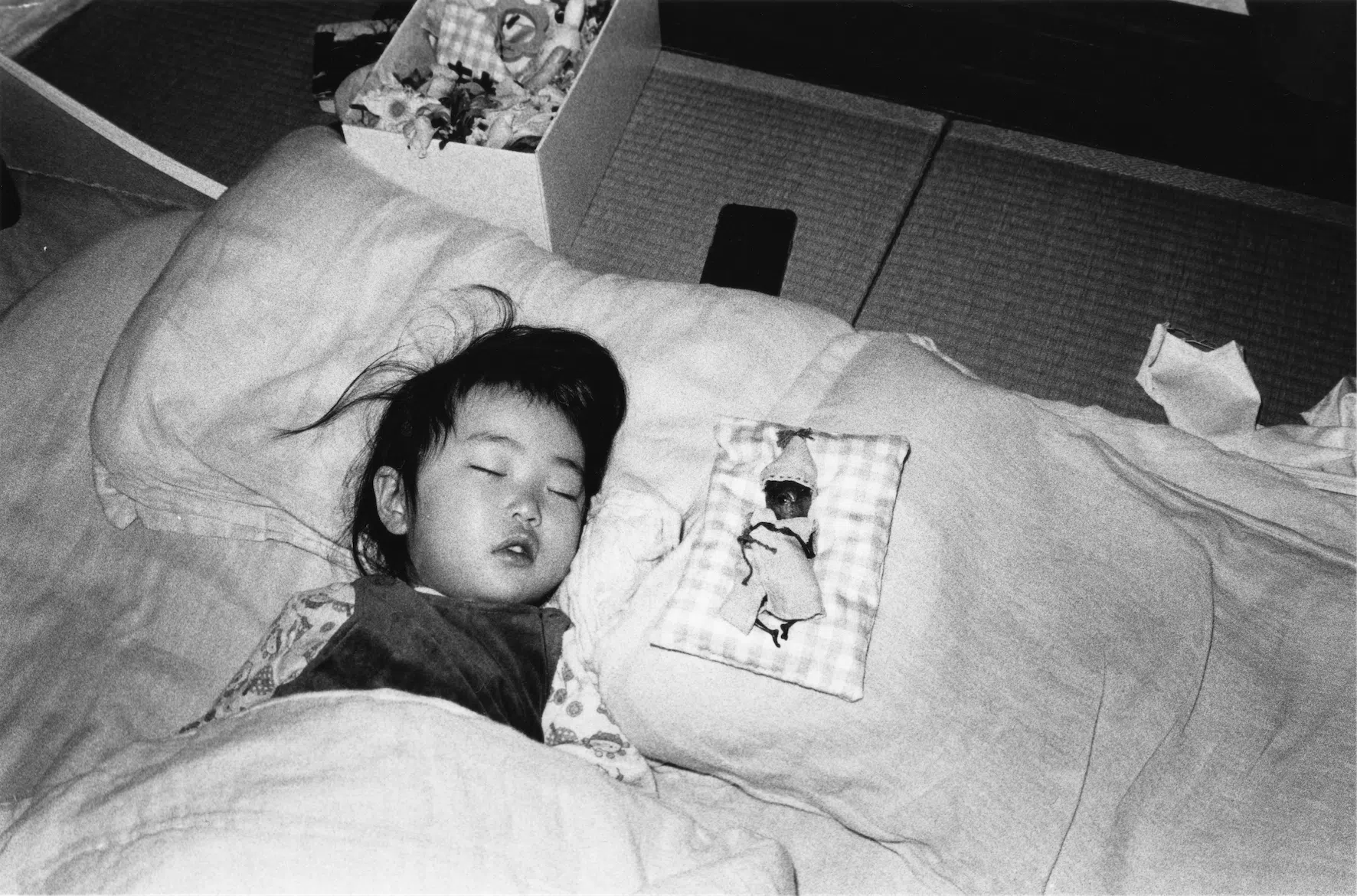 A young child asleep in a bed, shot as a black-and-white photograph