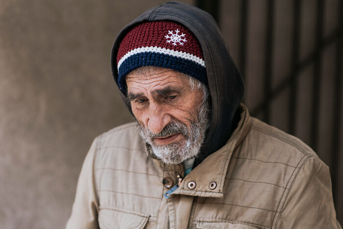 Elderly man in winter clothing looking down thoughtfully, illustrating cases of patients faking it in medical settings.
