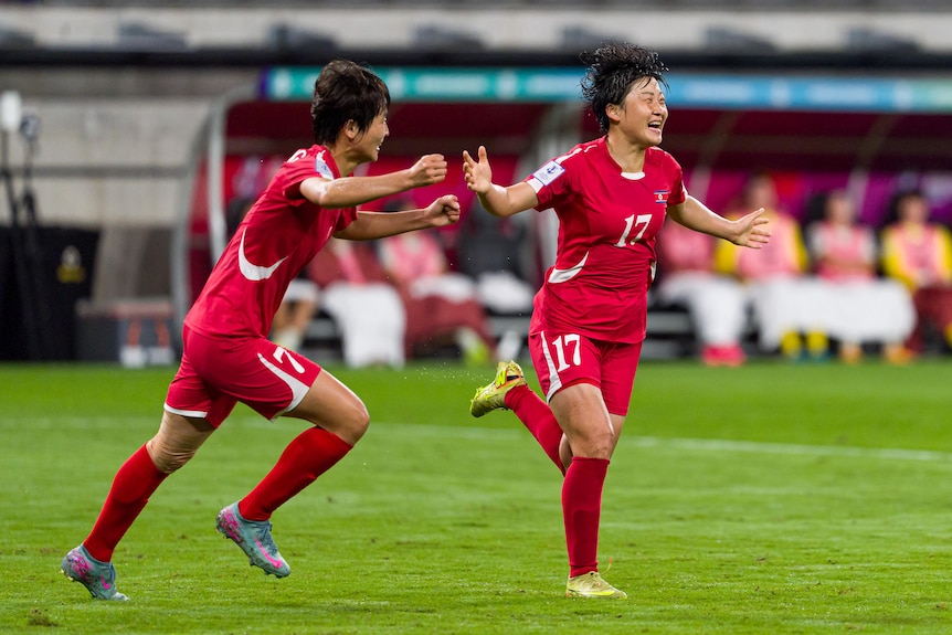 A North Korean player celebrates running with her arms stretched outwards