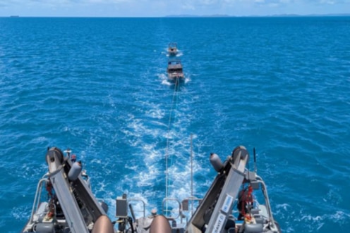 two boats in a long tow behind a ship