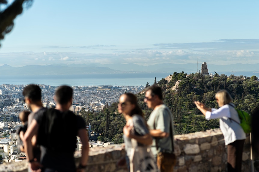 Tourists taking in a view of Athens from a high vantage.