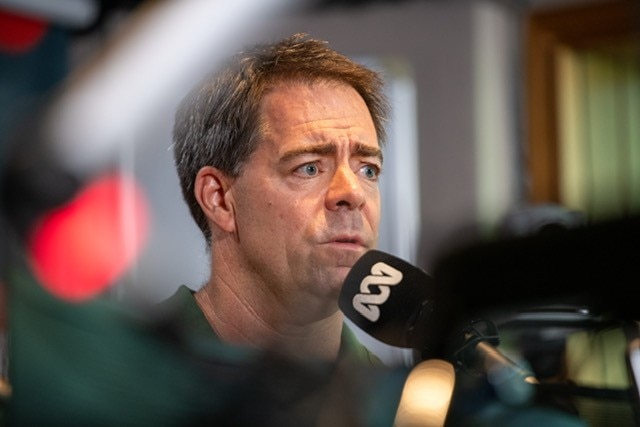 A worried looking man in headshot in front of an ABC microphone.