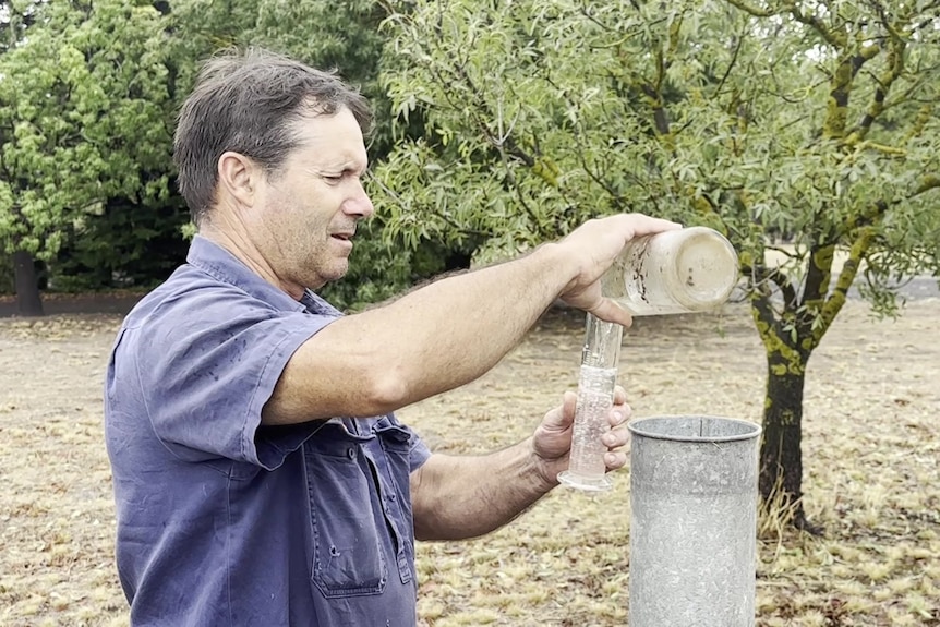 A man checks a rain gague on a farm