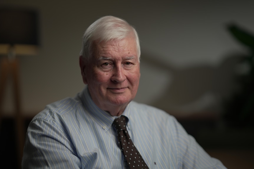 A man in a suit and tie looks into camera.