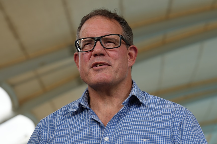A man with glasses speaking to the media.
