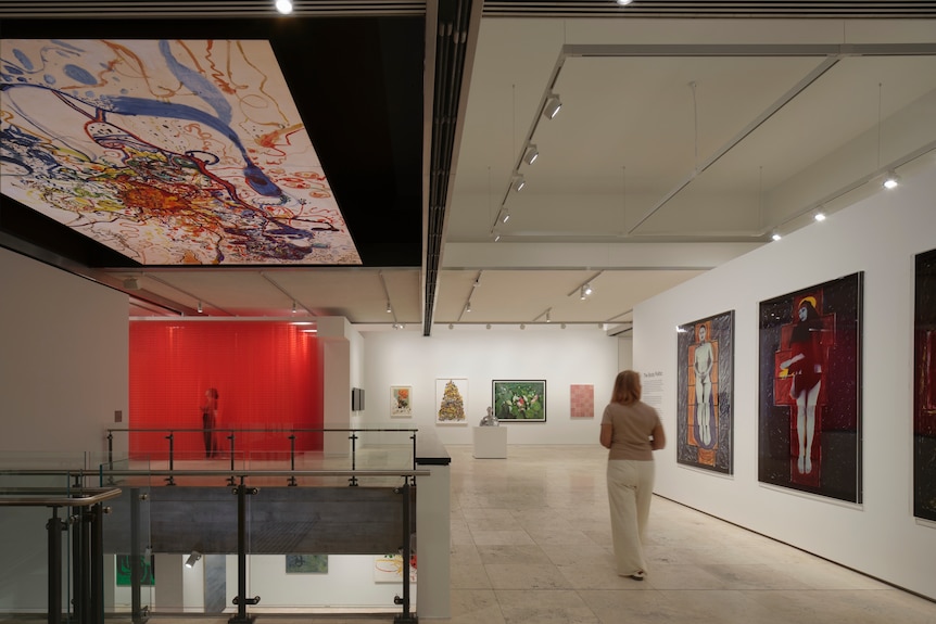A view of a gallery with artworks on the walls; The Sea Sun of 5 bells by John Olsen installed on the ceiling.