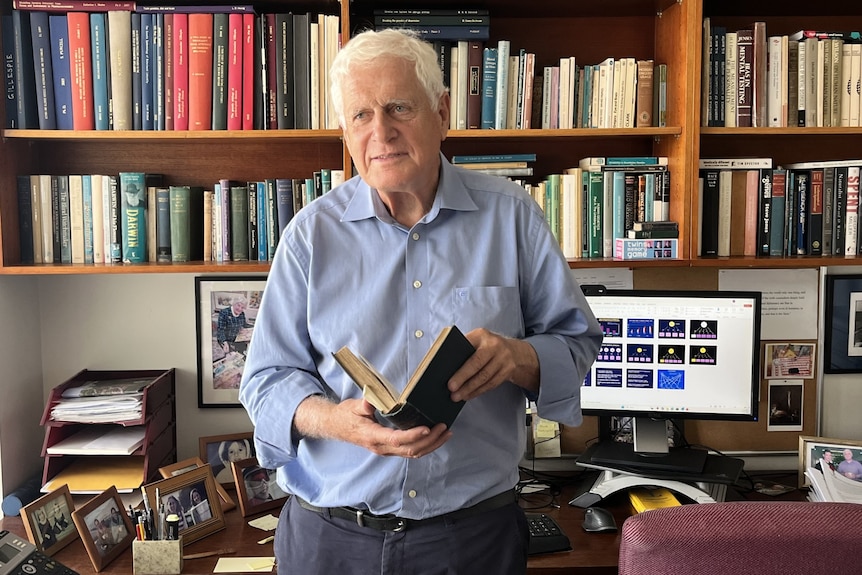 mature aged man reading a book in his office