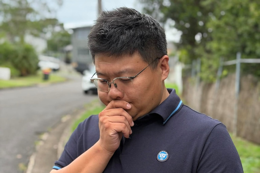 A photo of Billy standing outside and looking at his phone.