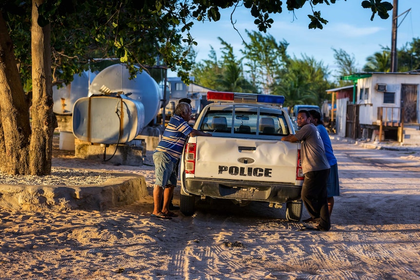 Four men lean on a police ute on Enetewak Atoll, Marshall Islands, October 2017.