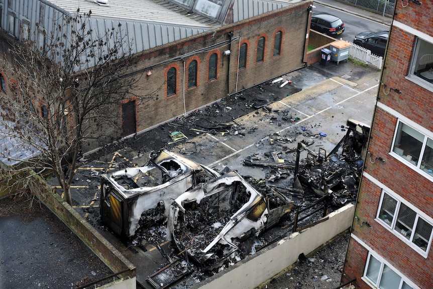 An aerial view of two vehicles in a carpark which have been destroyed by fire. 