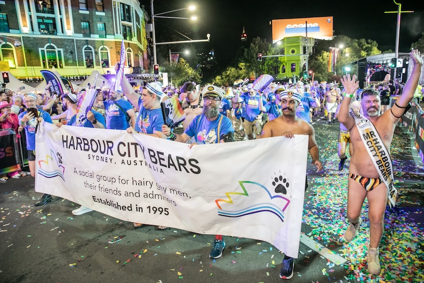 Men bare chested and men in blue shirts march Sydney's Mardi Gras parade.