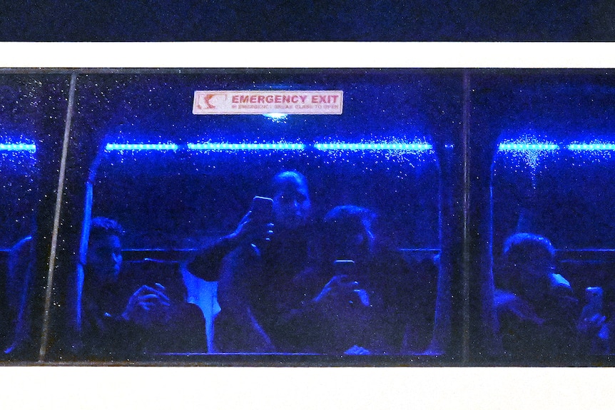 People attempting to block a bus full of soccer players