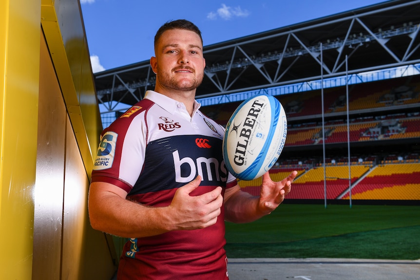 Queensland Reds and Wallabies hooker Matt Faessler posing with a rugby ball in an empty stadium.