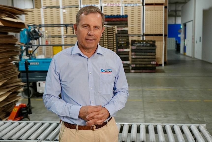 A man standing in a warehouse smiling at the camera.