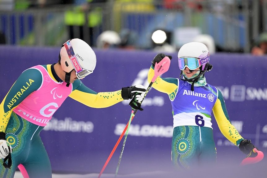 An Australian para-alpine skier smiles as her guide reaches out to her after their slalom run at the Winter Paralympics.