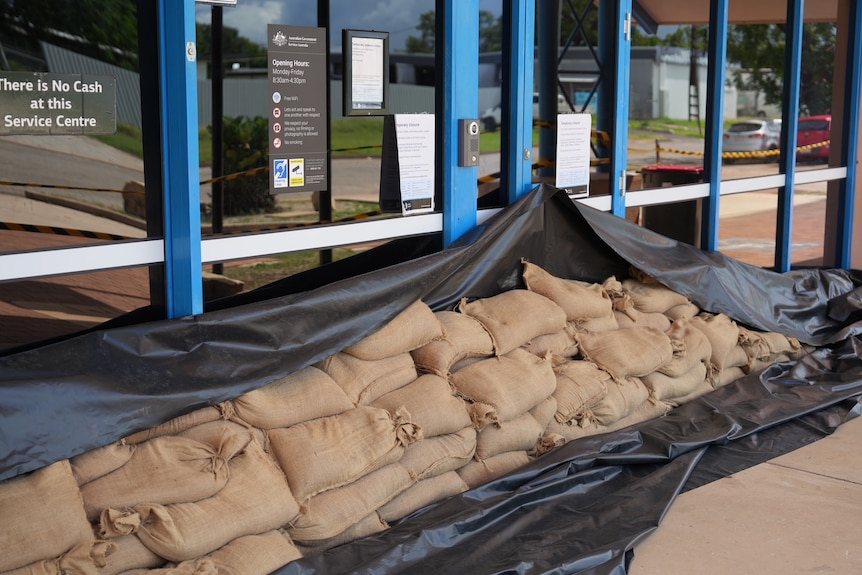 A black tarp and sandbags block the front door of a building in town.
