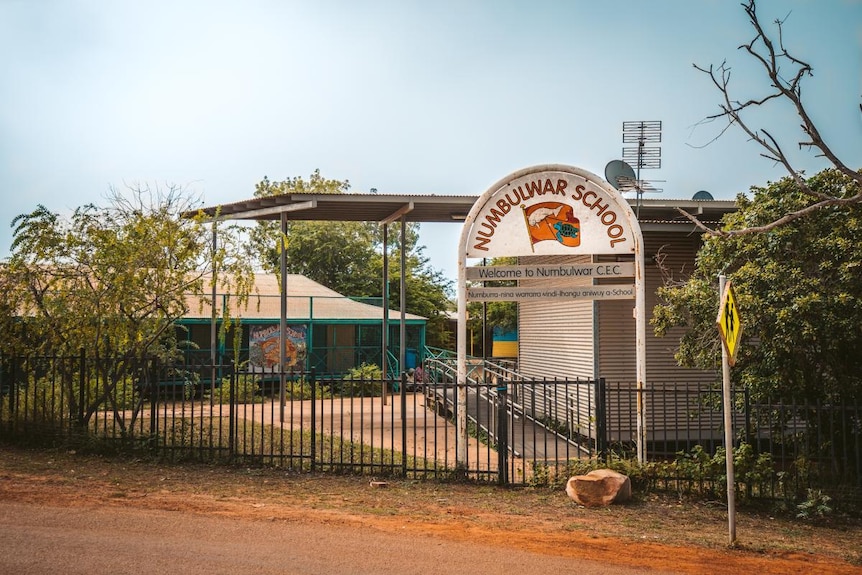 The exterior of a school in a remote community, with an entrance sign out the front.