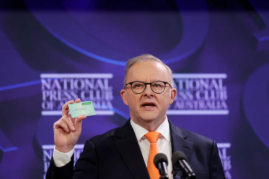 anthony albanese holds up medicare card