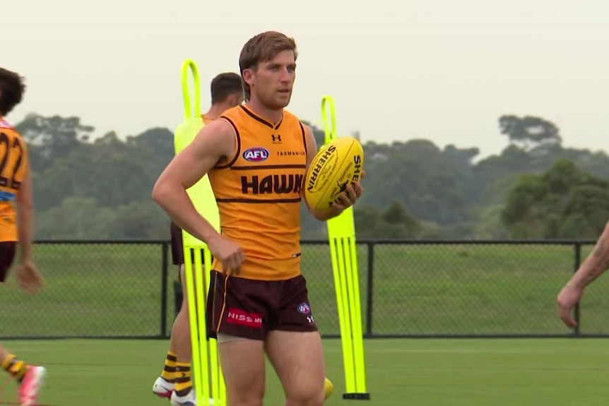 Dylan Moore holds a football while on a football field.