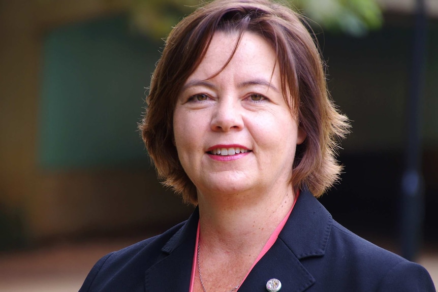 A smiling woman with short brown hair weather a blue blazer.