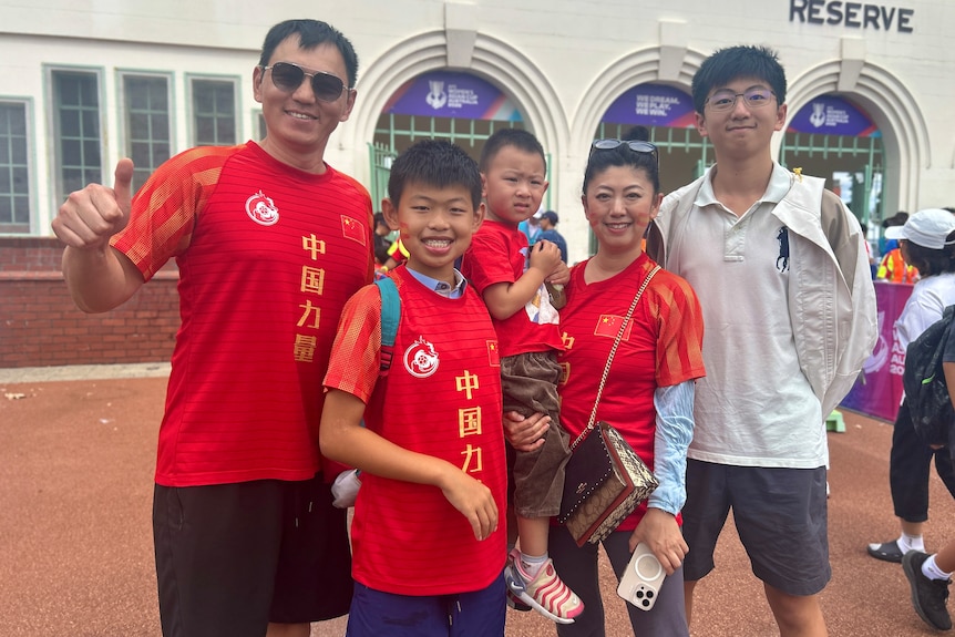A group of people in red China jerseys smile at the camera with one in grey