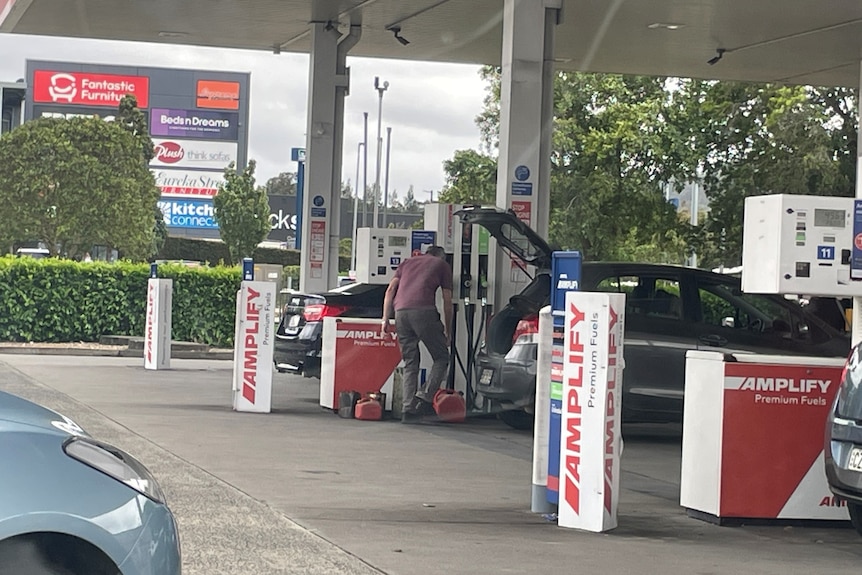 A man fills jerry cans with petrol 