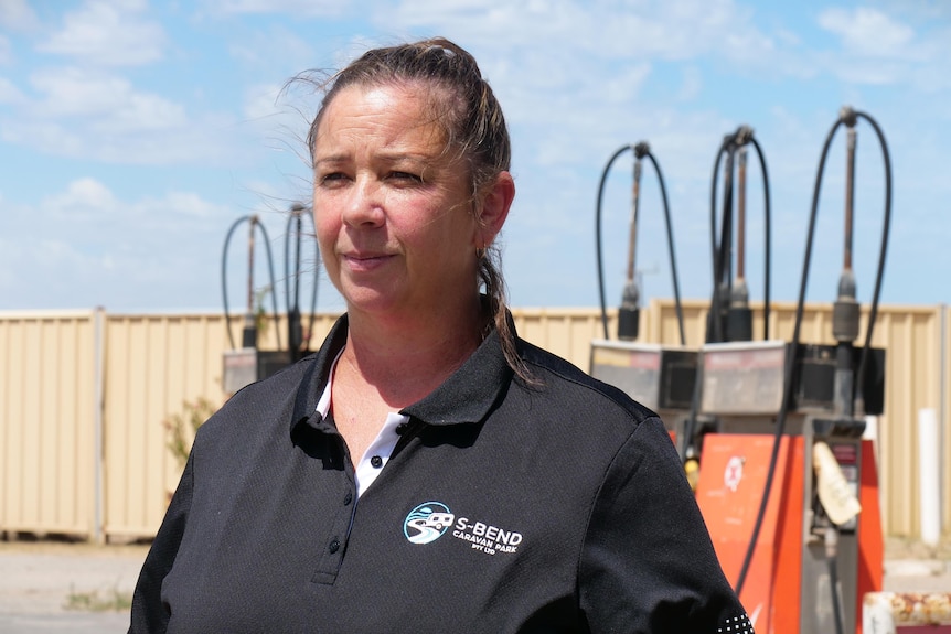 A woman wearing a black polo t-shirt in front of petrol bowser