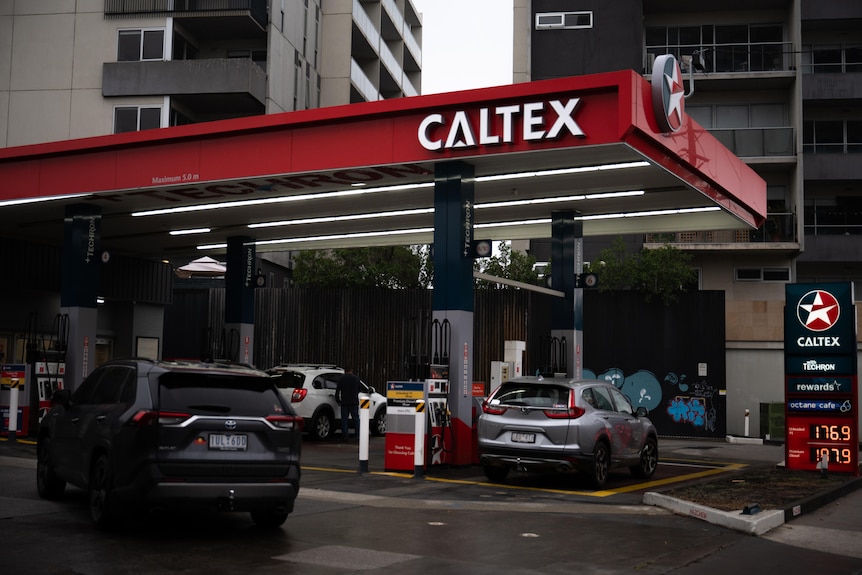 Cars piling into a service station, large caltex sign on red background, night.