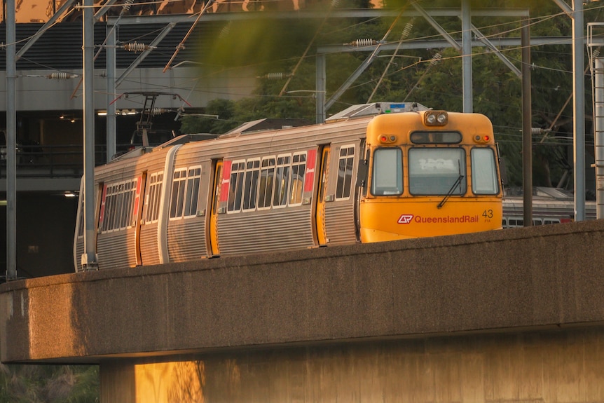 A metro train emerges from a covered station on an elevated track.