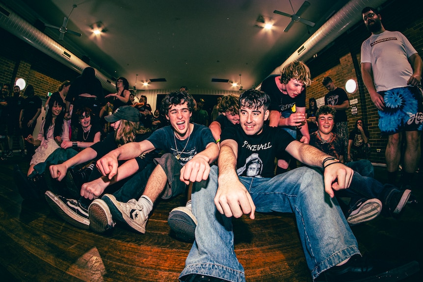 Young men and women smile as they sit and enjoy the live music.