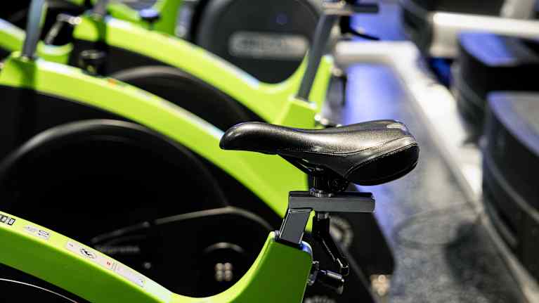 A row of light green stationary exercise bicycles.