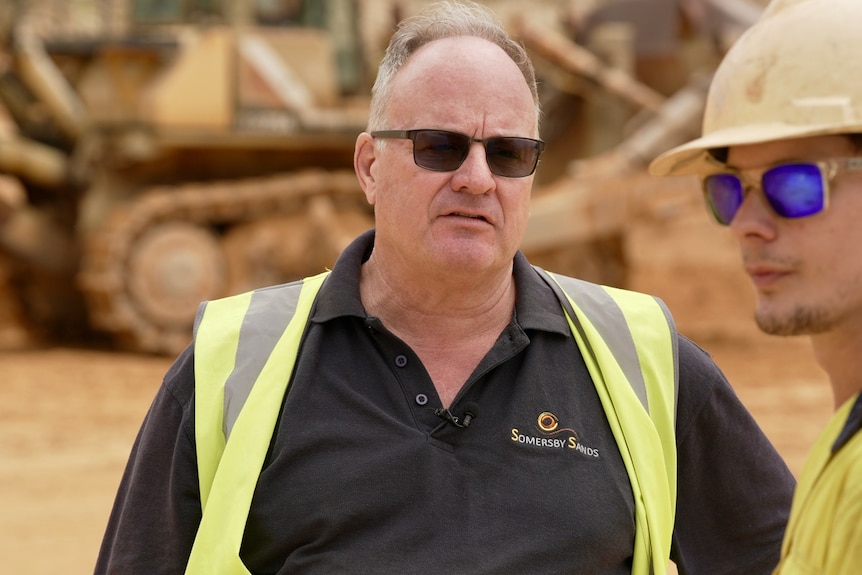 A man wearing a high-vis vest and sungalsses. 