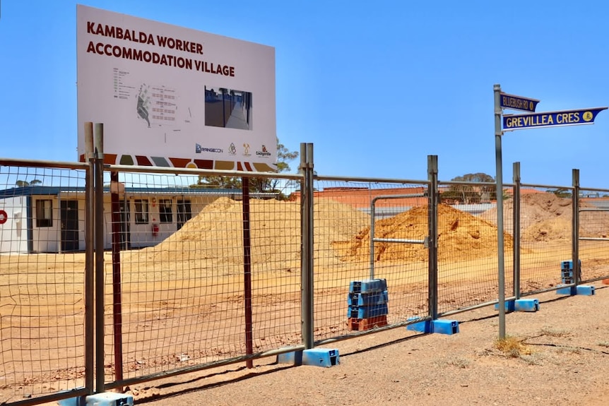 Construction of a mining camp behind a fenced off site.  