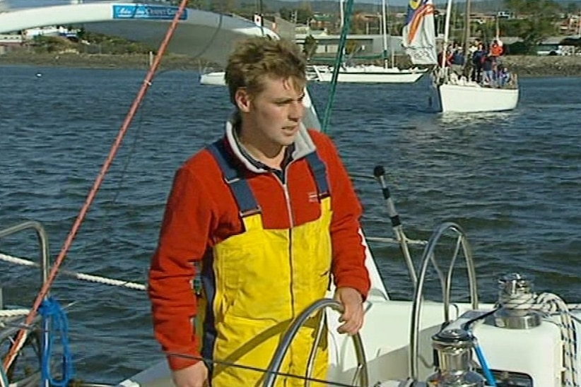A young man at the helm of a sailing boat.