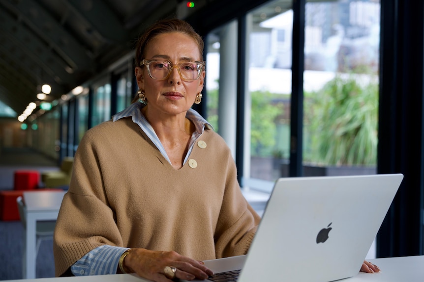 Private Healthcare Australia’s CEO sits at a laptop.