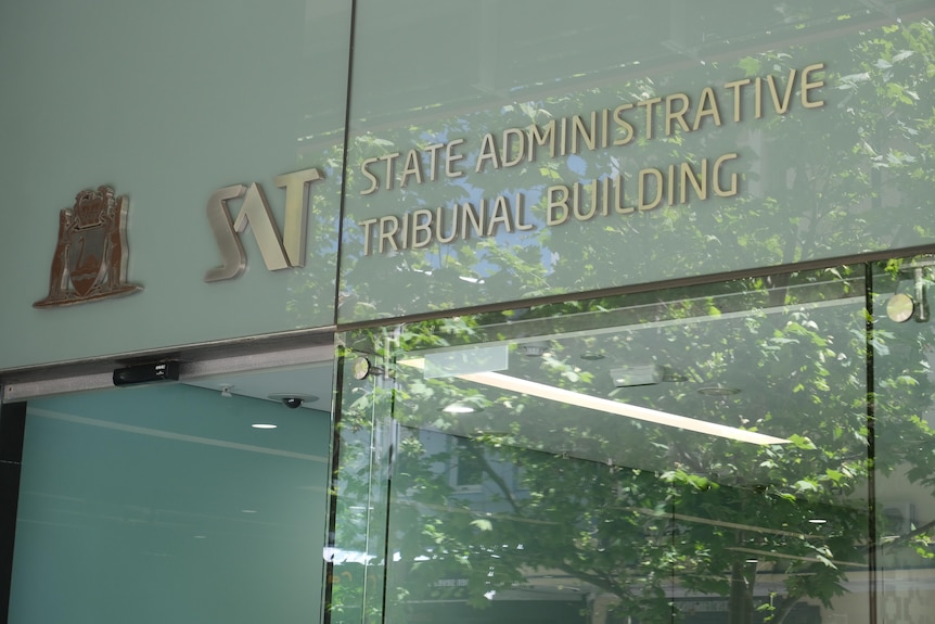 A glass wall with the words 'State Administrative Tribunal' written on it. 