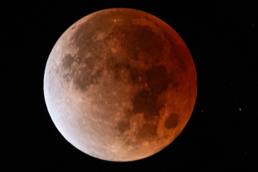 Close up image of the moon with orange, grey and white gradient