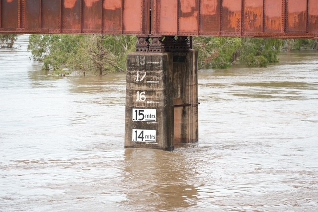 Water rushing past a bridge support column with a measurement on it. The water is sitting at 13.5m