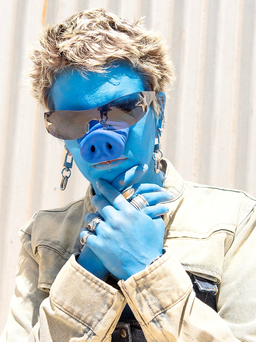 Girl painted blue with a blue pig nose on.