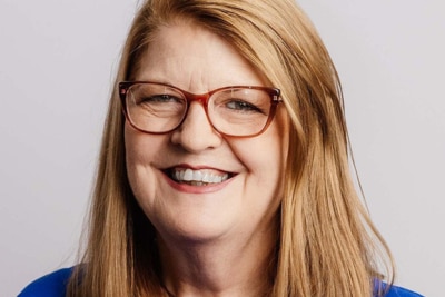 A woman with glasses smiling