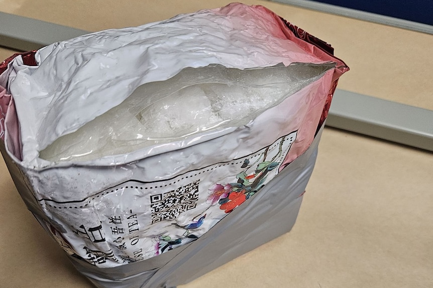 A plastic wrapped pack of multiple white blocks and screen saying methanphetamine.