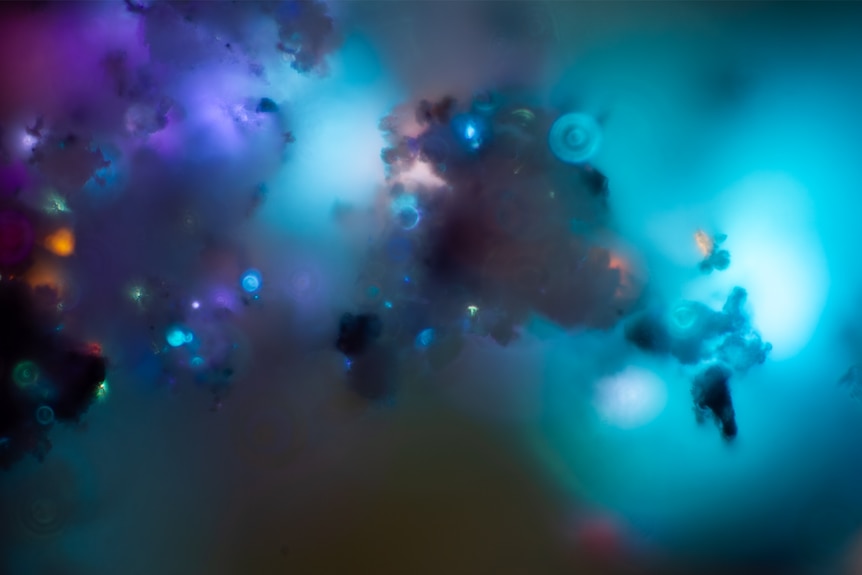 A swirling mixture of purples and blues punctuated by dabs of orange, mirroring a distant nebula.