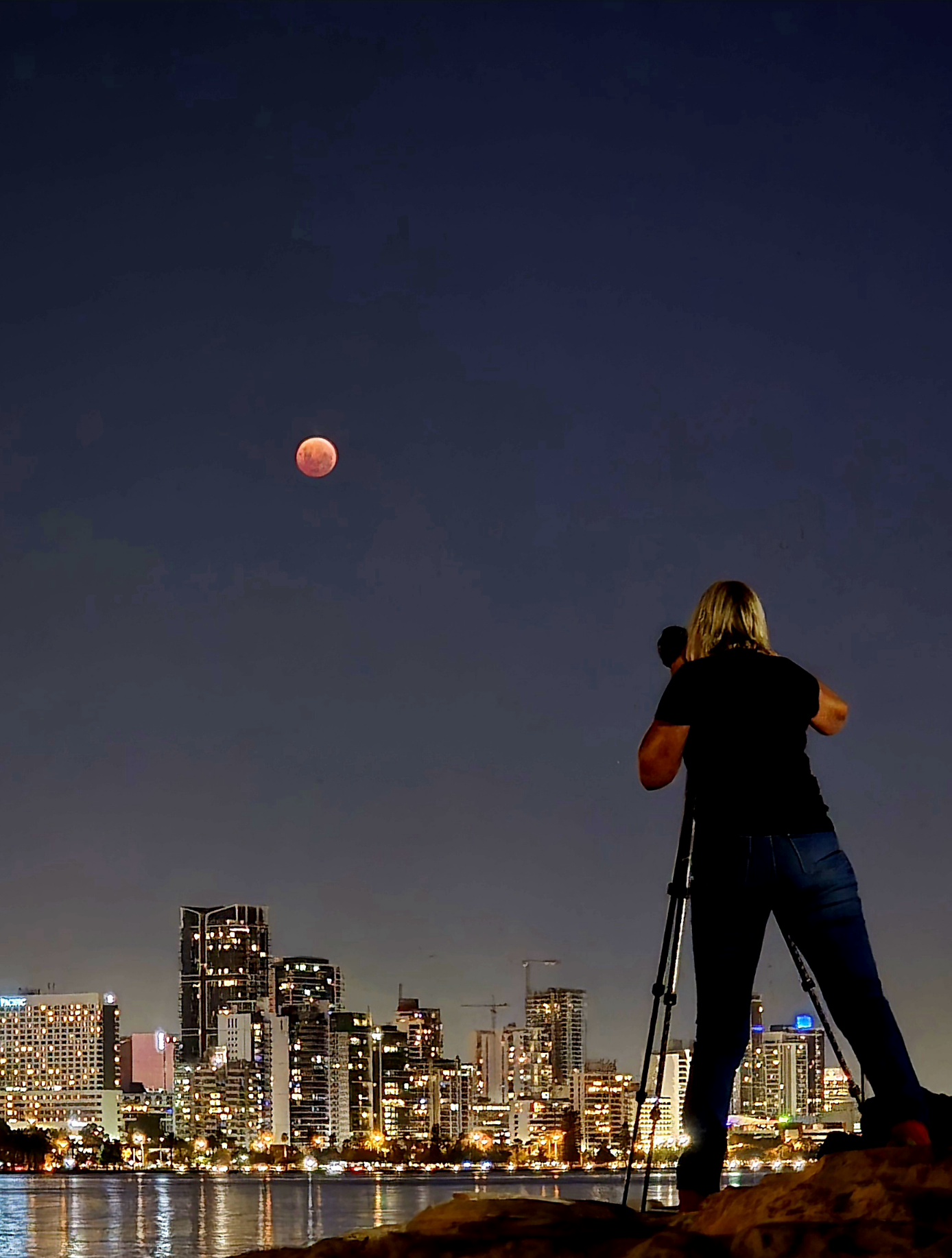 A photographer with a tripod taking a photo of the moon