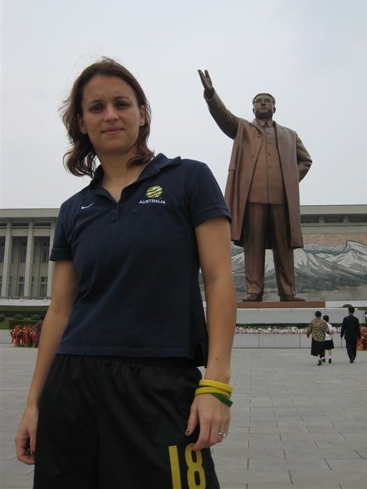 Melissa Barbieri poses for a photo in front of a statue in North Korea