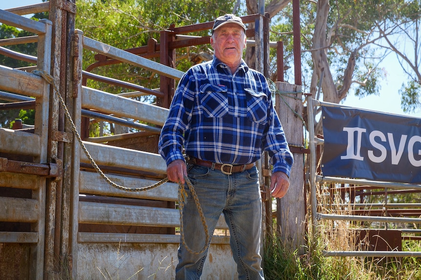 A man stands in the middle of a rodeo ring holding a rope
